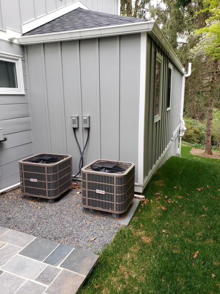 Two air conditioners are sitting on the side of a house.