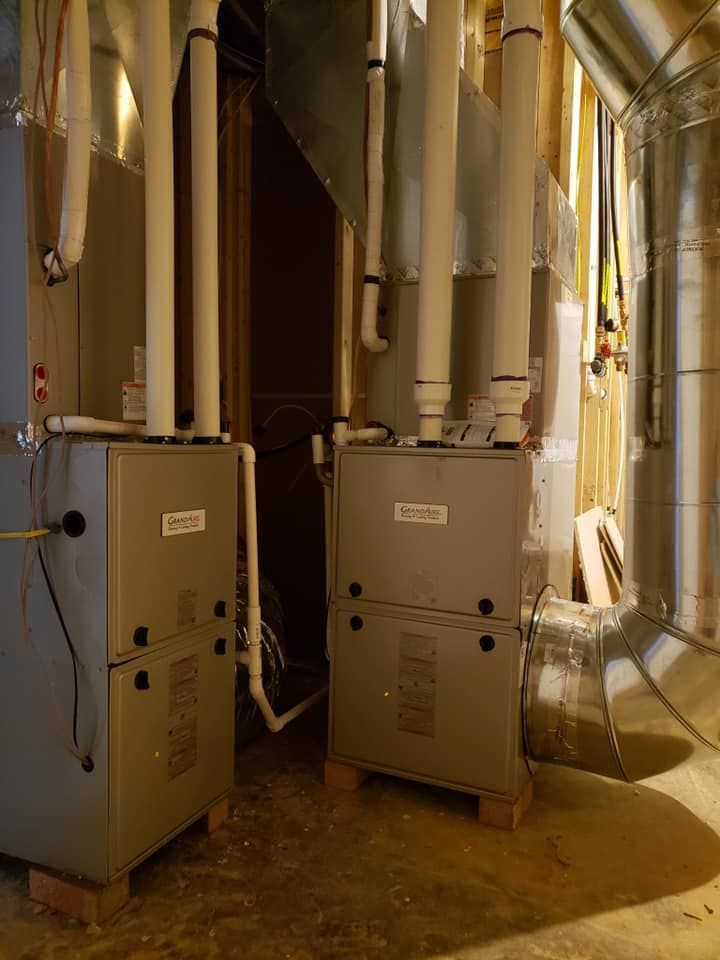 two air conditioners are sitting next to each other in a basement .