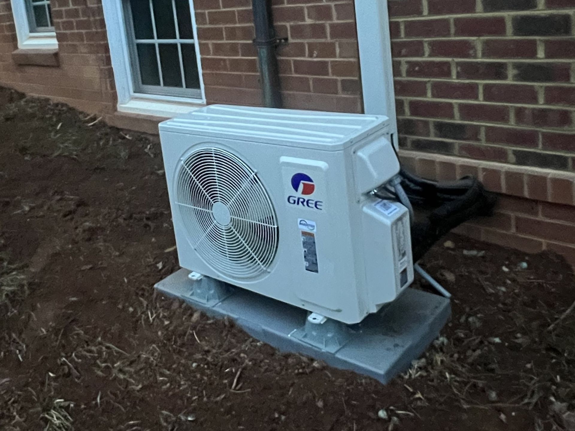 A white air conditioner is sitting outside of a brick building.