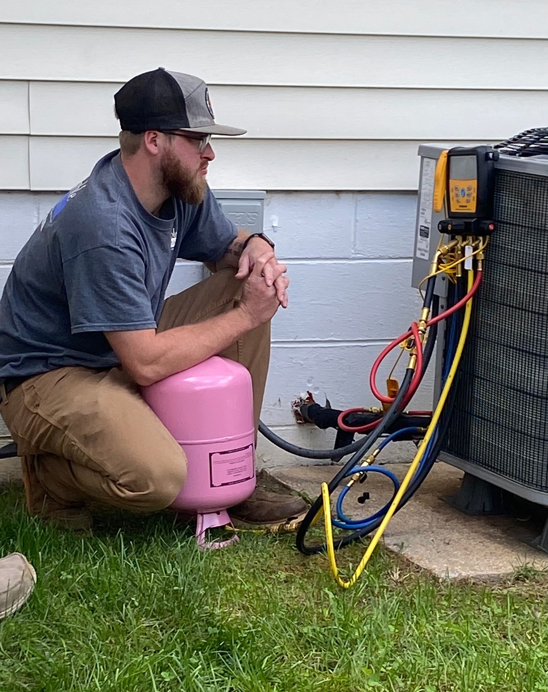 a man is kneeling down next to a pink tank of gas .