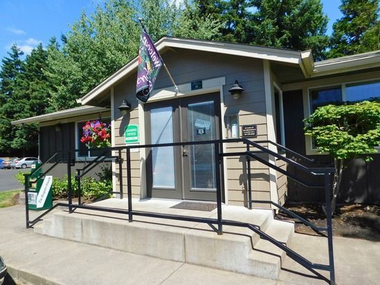 Apartment office building entrance with dark doors, railings, and a flag.