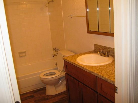 Bathroom with a white tub, toilet, and sink with a brown countertop and cabinets.