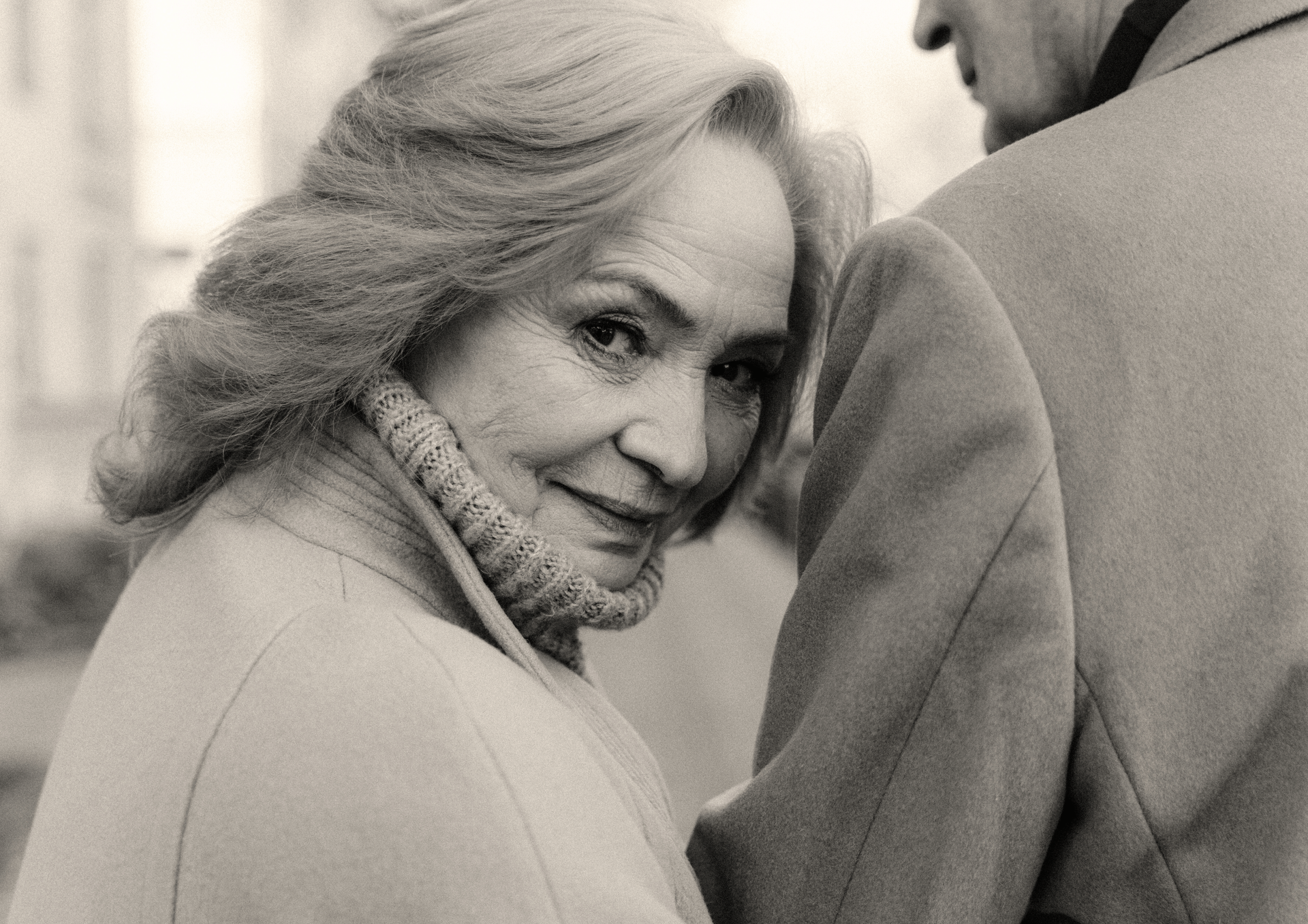 A black and white photo of a woman hugging a man.