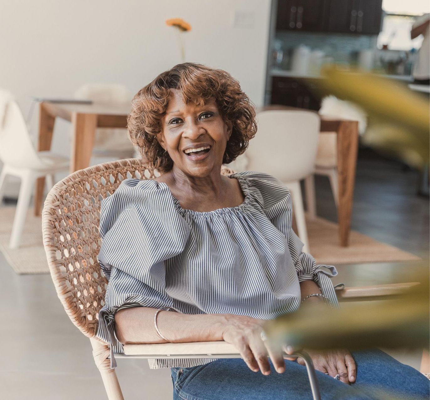 An elderly woman is sitting in a chair and smiling.