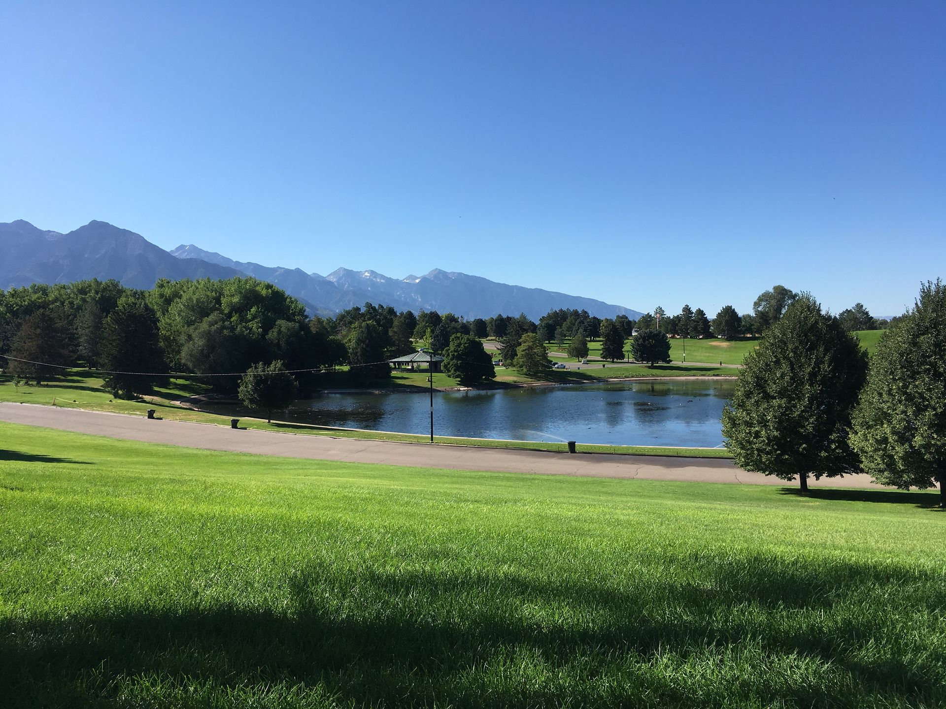 there is a lake in the middle of a park with mountains in the background .