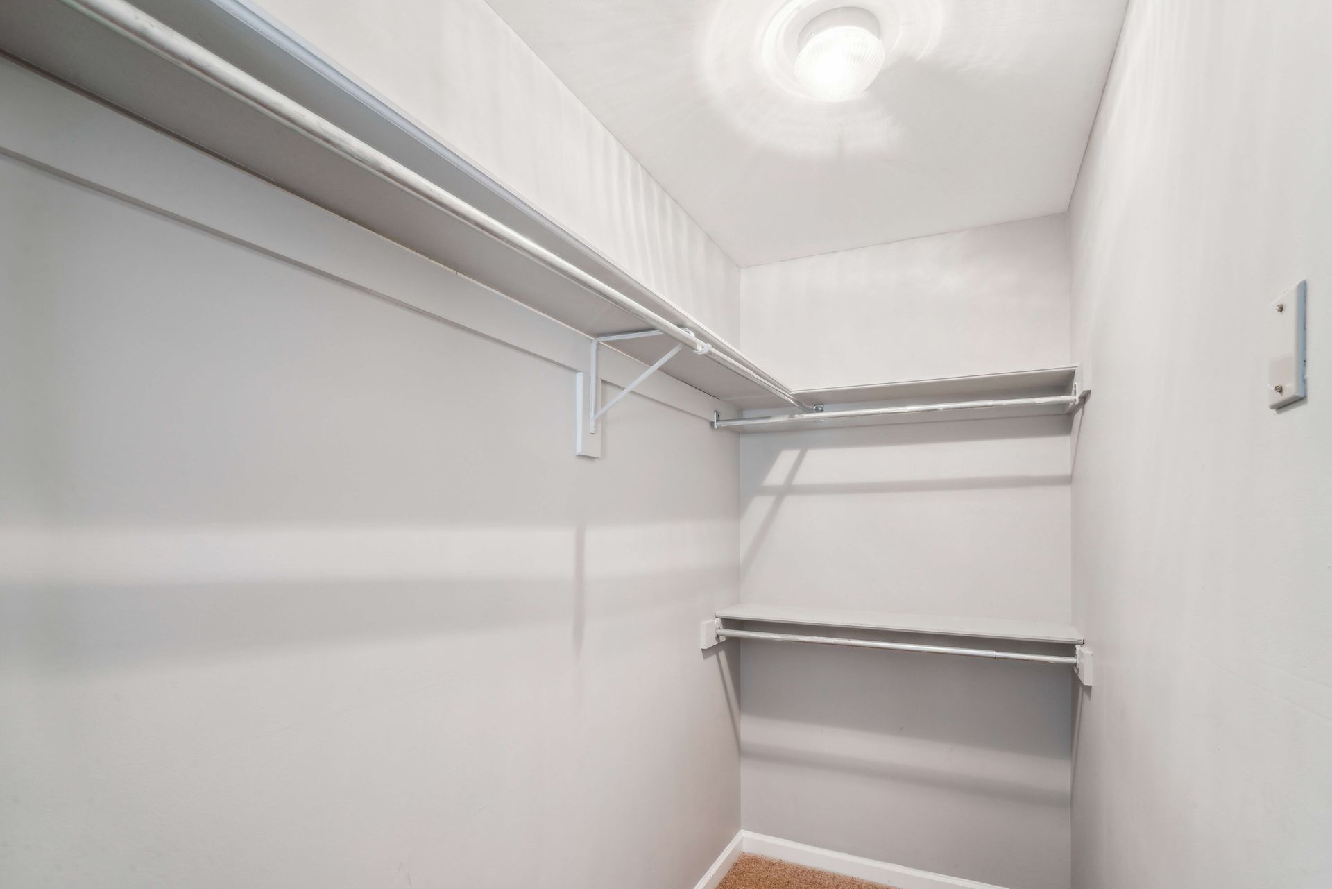 Empty white closet with wire shelving and hanging rod