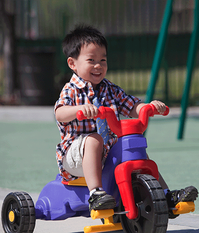 young asian boy riding a tricycle