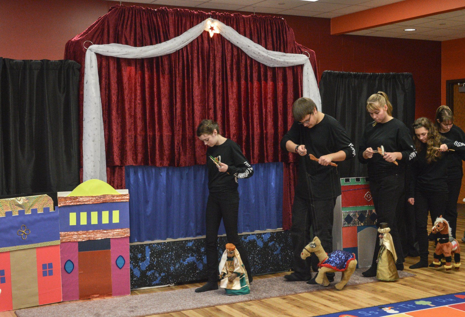 Wise men and camel marionettes trek in front of the stage