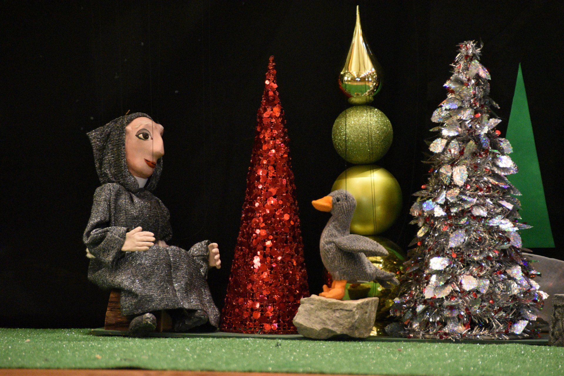 Our Mother Goose marionette begins to narrate her story as the Priest looks on