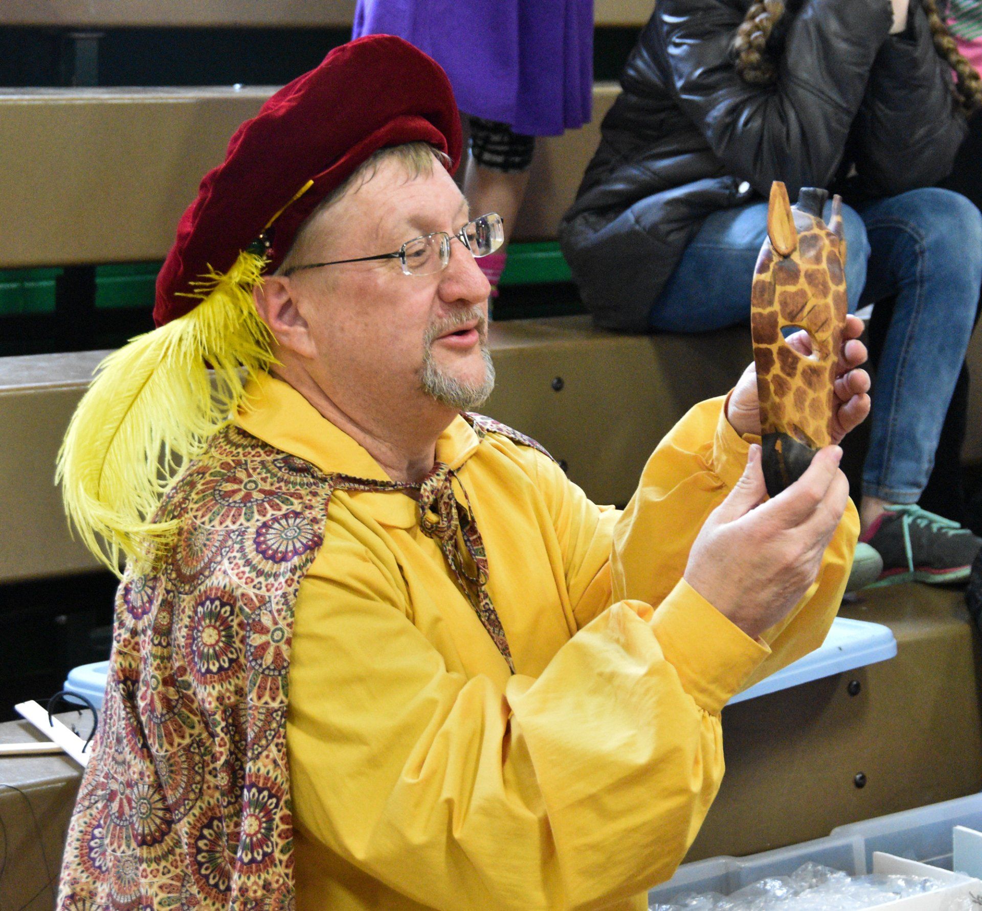Mr. Dave holds up a giraffe mask for workshop participants