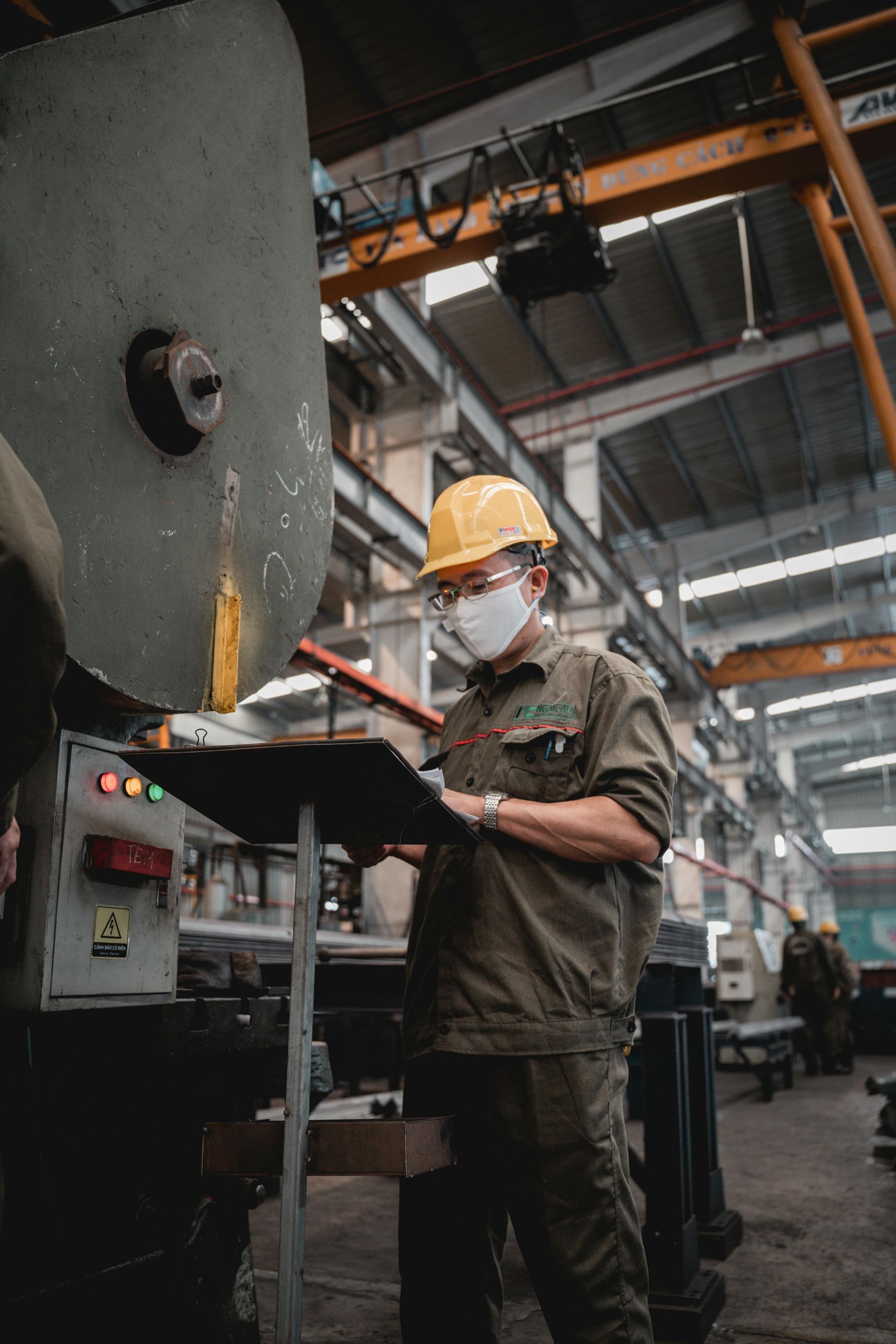 Ouvrier portant un casque de chantier manipulant une machine industrielle dans un atelier d'usine