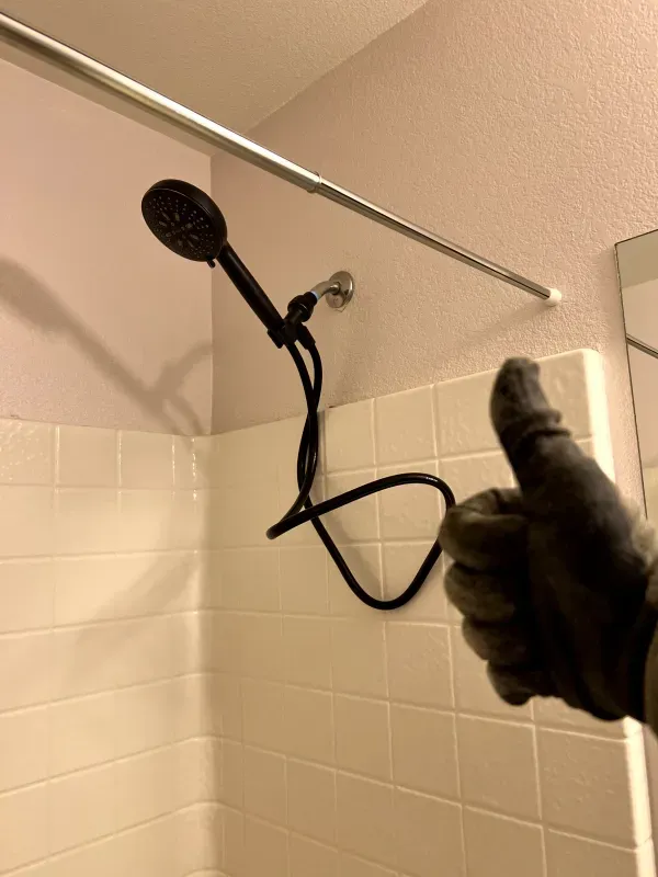 A person giving a thumbs up next to a shower head