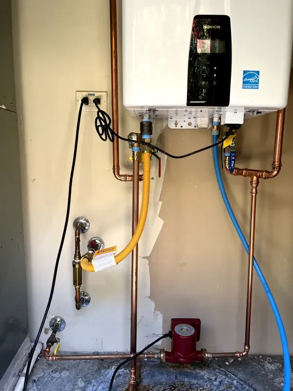 A water heater is connected to copper pipes in a room.