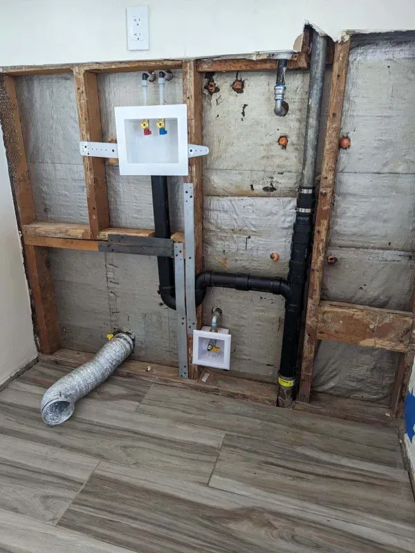 A bathroom with a washer and dryer being installed in the wall.