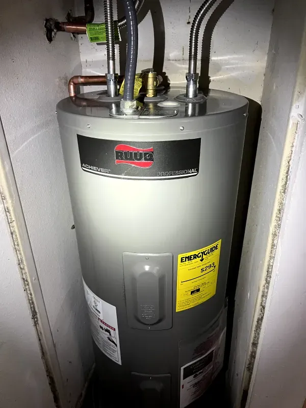 A water heater is sitting in a corner of a room.