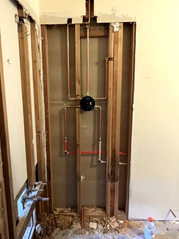 A bathroom with a hole in the wall and pipes coming out of it.