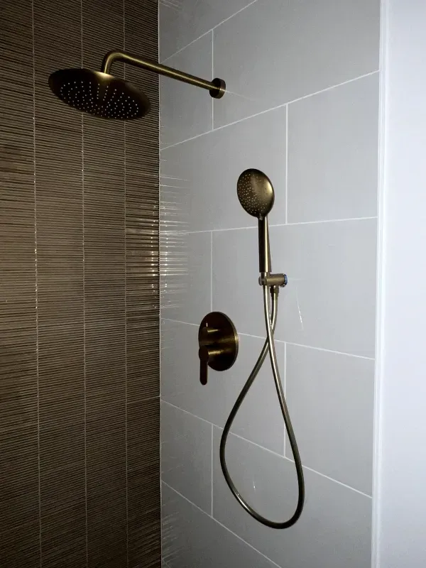 A close up of a shower head and shower head in a bathroom.