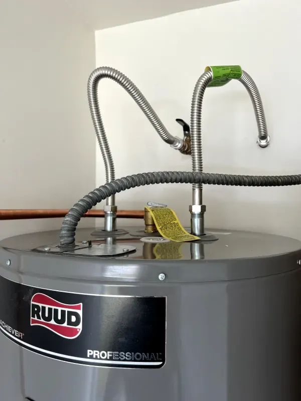 A ruud water heater with a hose attached to it
