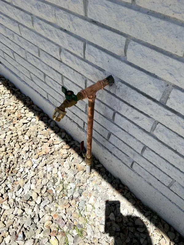 A faucet is attached to the side of a brick wall.