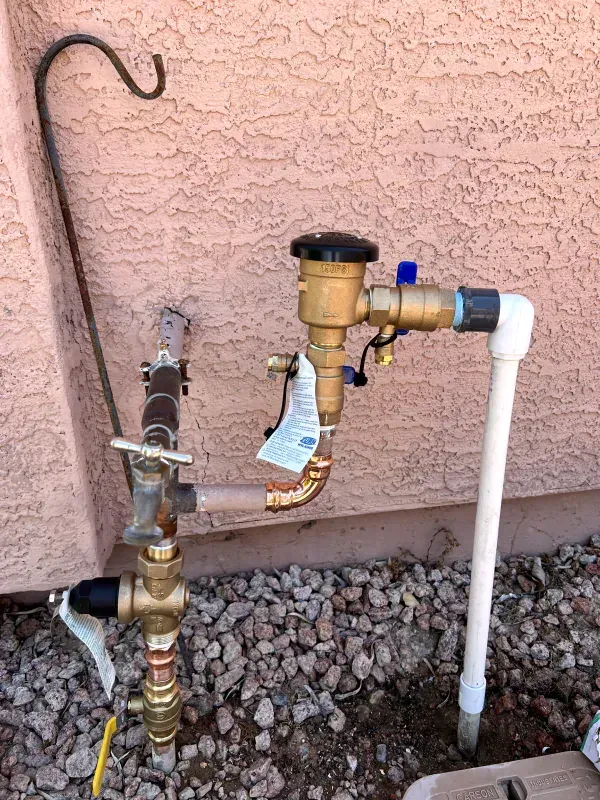 A hose with a valve attached to it is sitting next to a wall.
