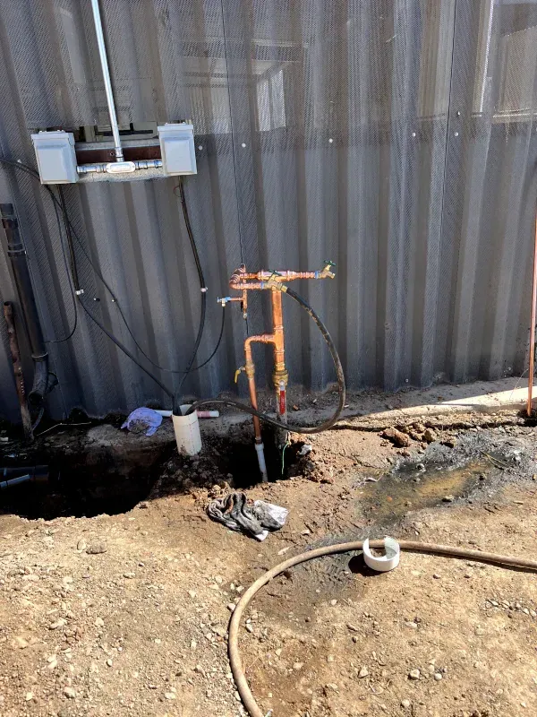 A hose is laying on the ground next to a pipe.