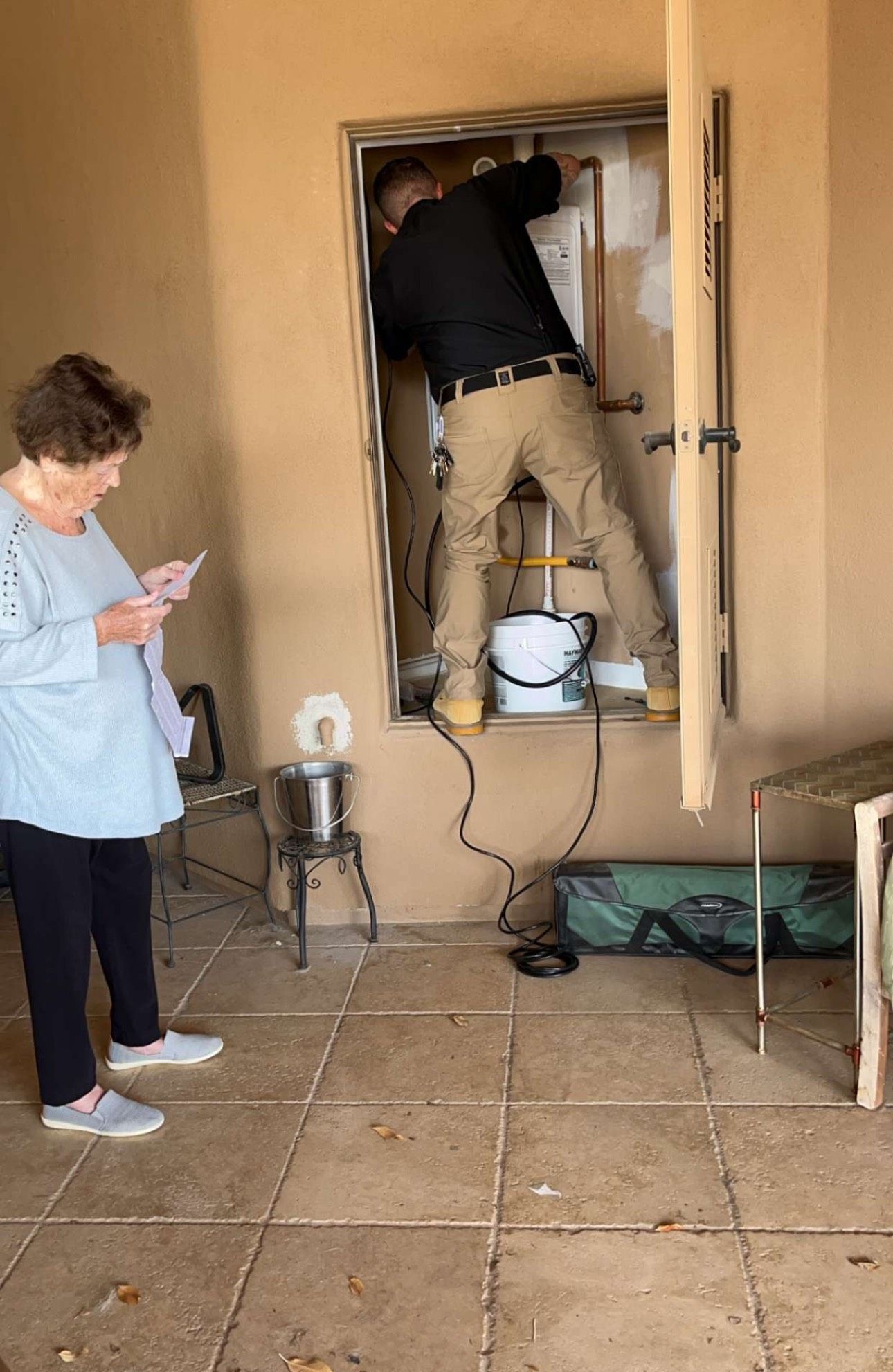 A man is working on a wall while a woman looks on.