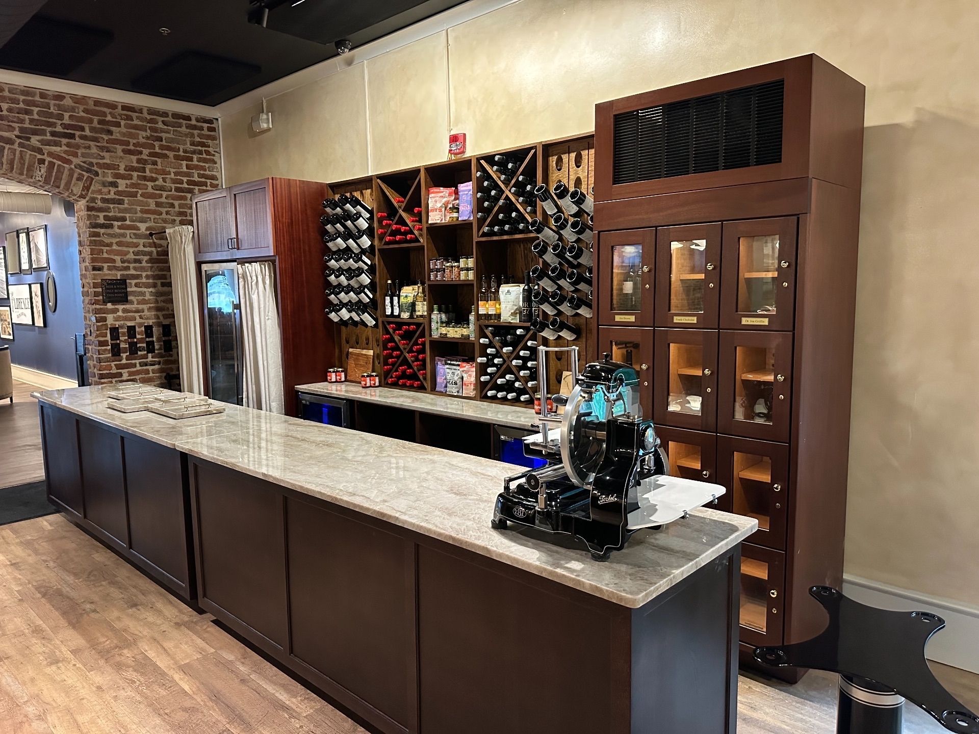 Wine bar interior with wooden shelves, granite countertop, and wine bottles.