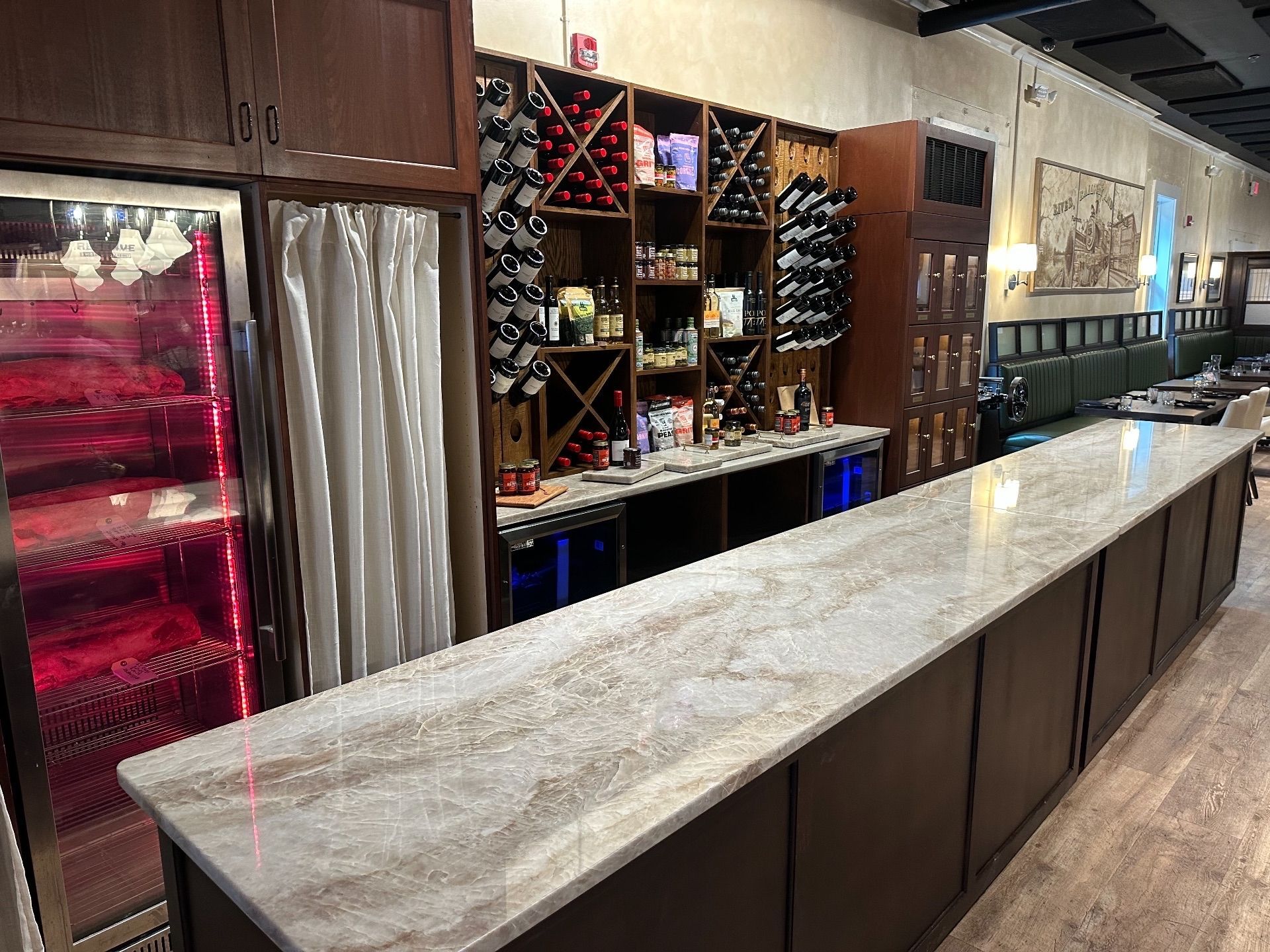 Restaurant bar with marble countertop, wine racks, and a glass-door refrigerator.