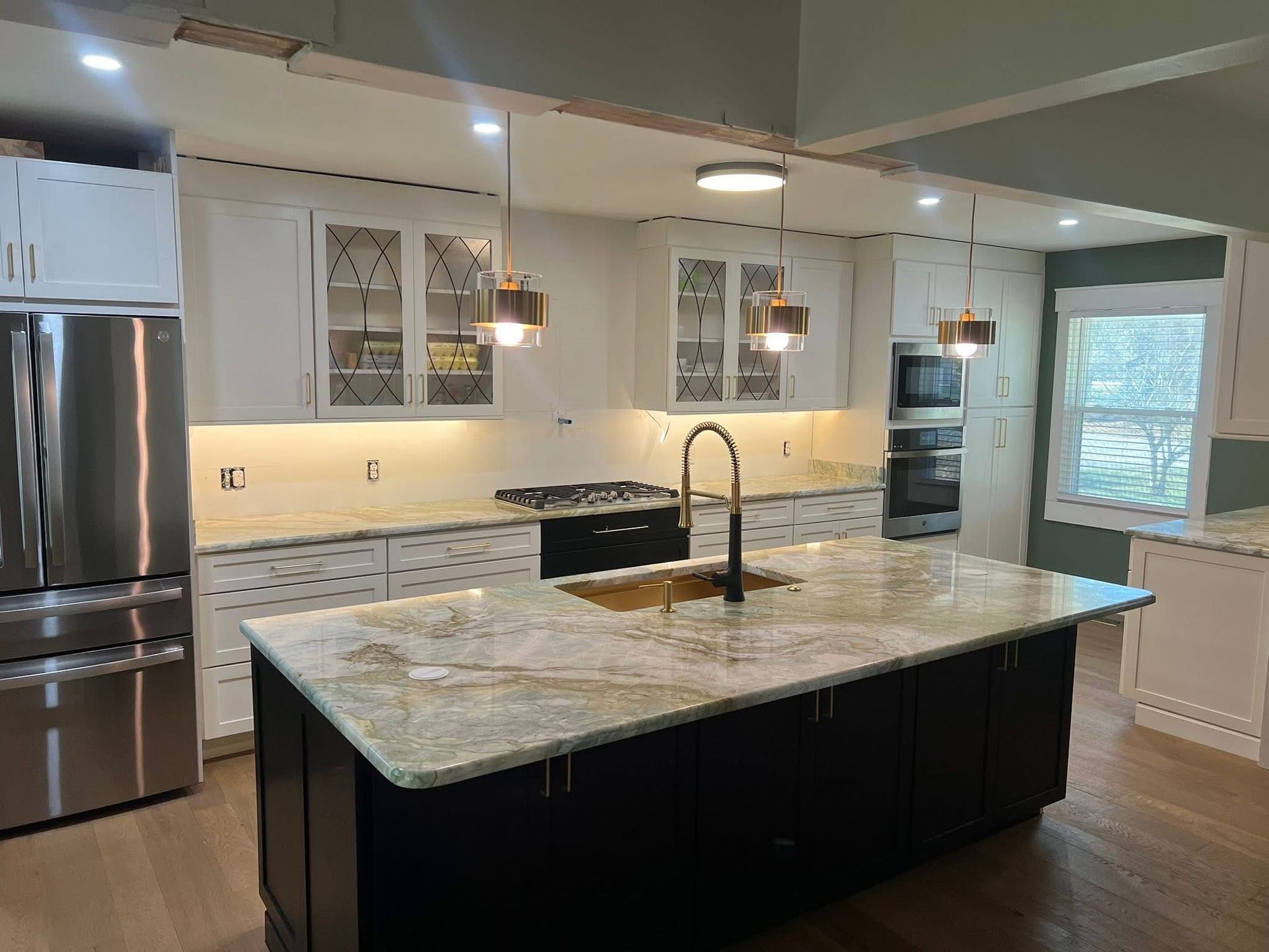 Newly renovated kitchen with white cabinets, dark island, and gold accents.