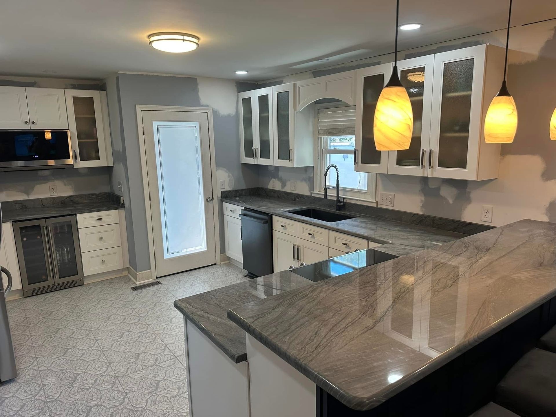 White kitchen with granite countertops, white cabinets, and pendant lights.