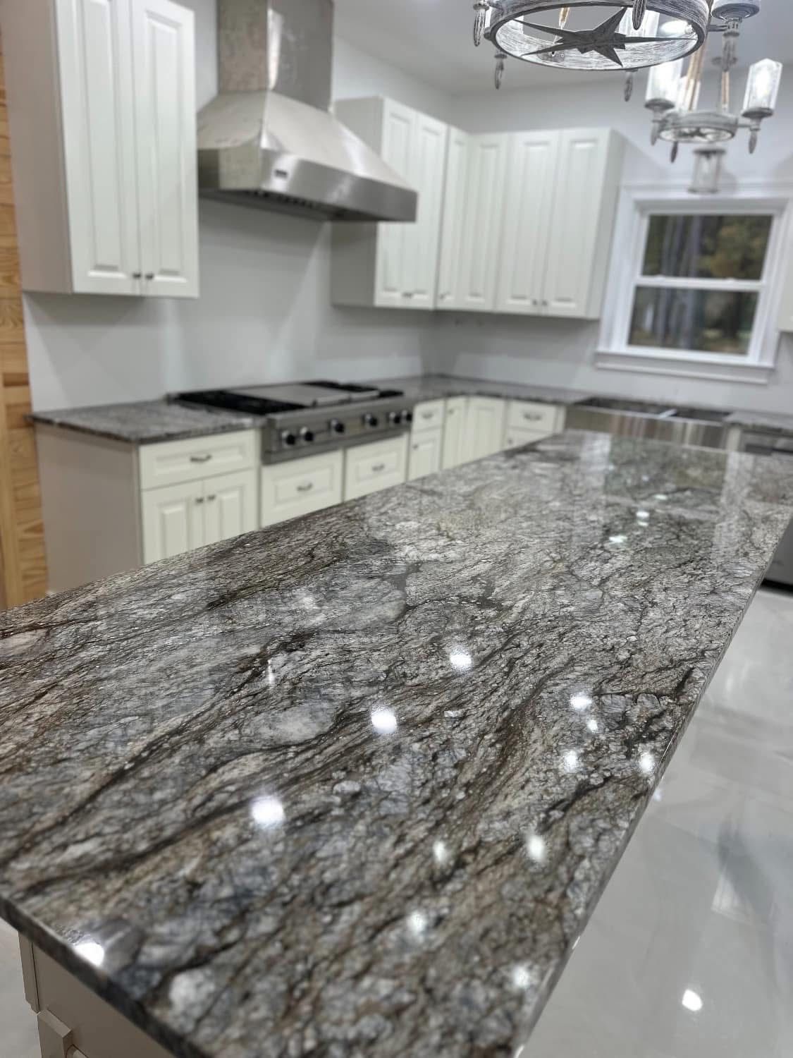 Kitchen with white cabinets, stainless steel appliances, and a granite countertop with swirling gray and brown patterns.