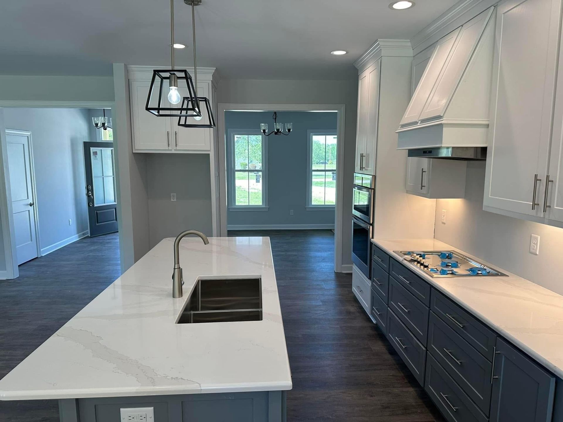 Kitchen with white and gray cabinets, island with sink, and appliances.