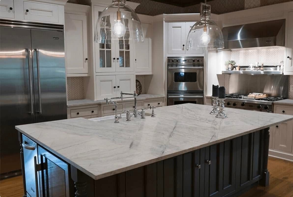 Elegant kitchen with a marble countertop island, stainless steel appliances, and glass pendant lights.