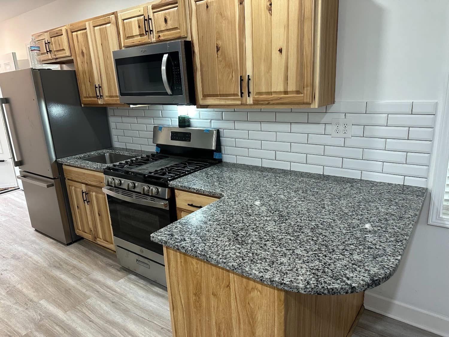 Kitchen with light wood cabinets, gray countertops, stainless steel appliances, and white subway tile backsplash.