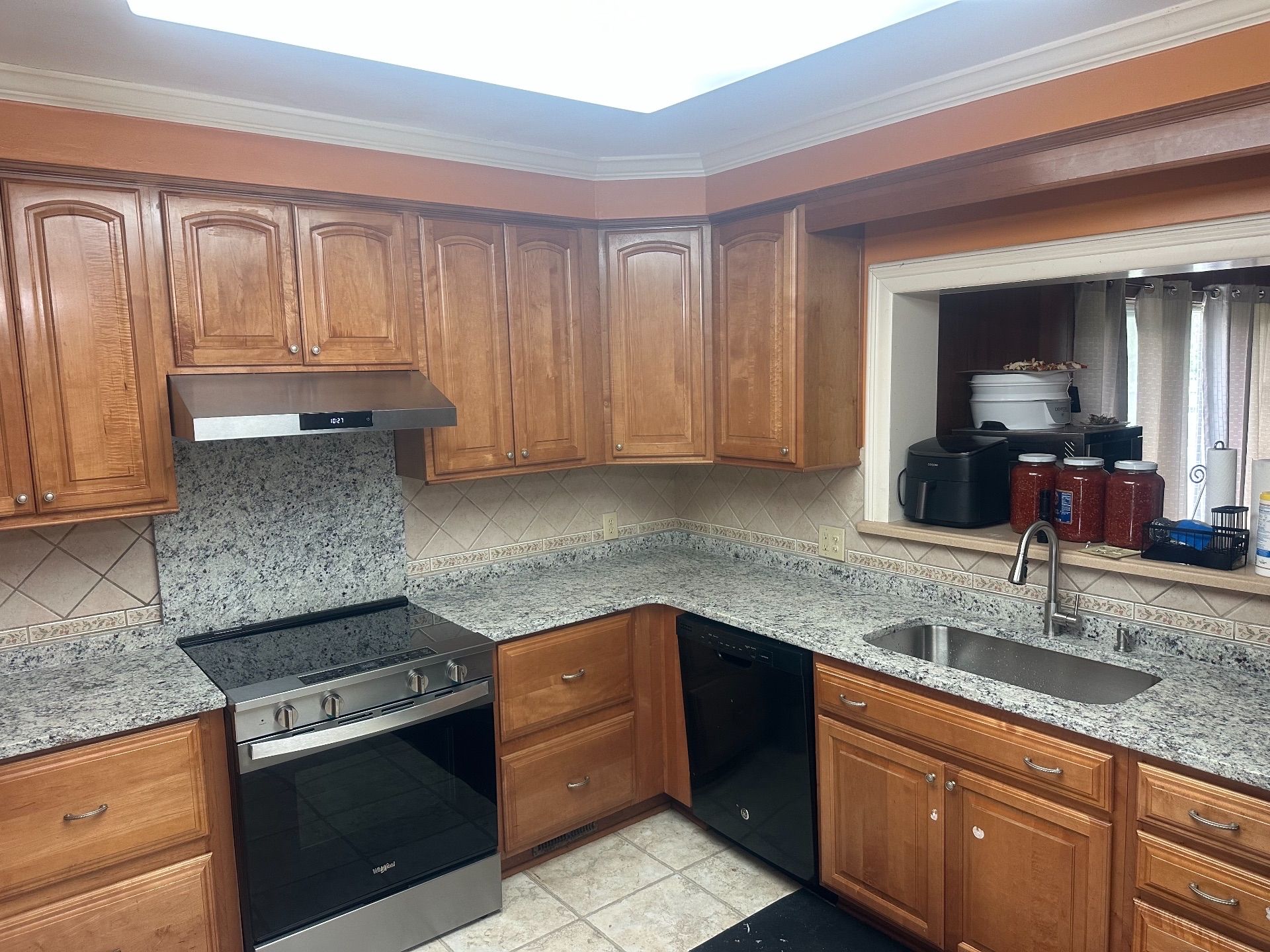 Kitchen with brown cabinets, granite countertops, stainless steel appliances, and a window.