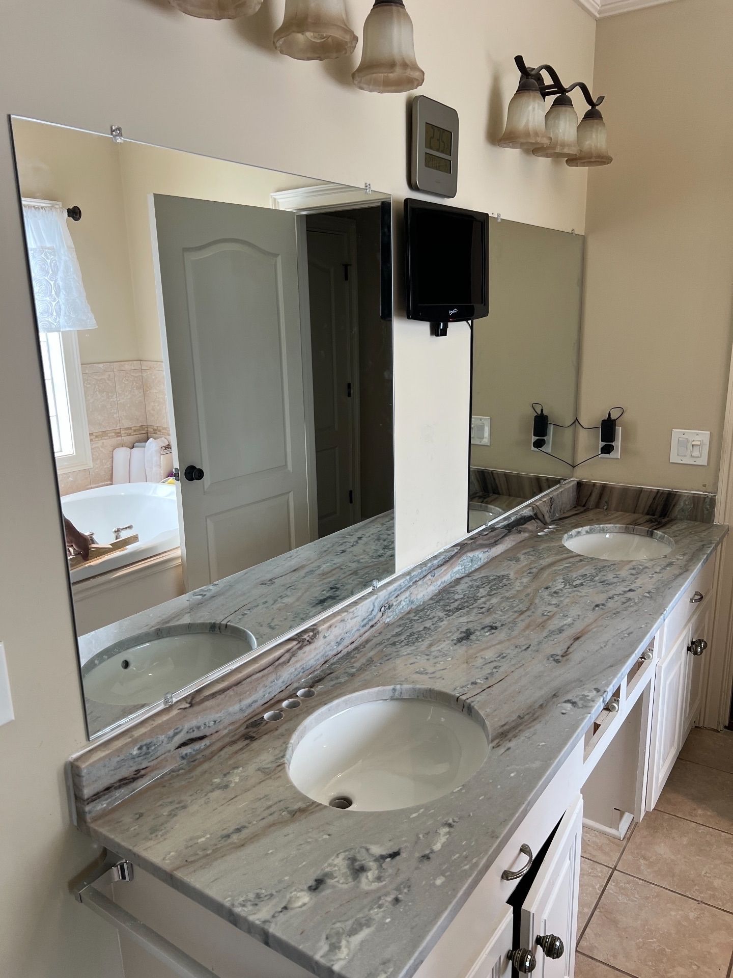 Bathroom with large mirror over double vanity with marble countertop and two sinks.