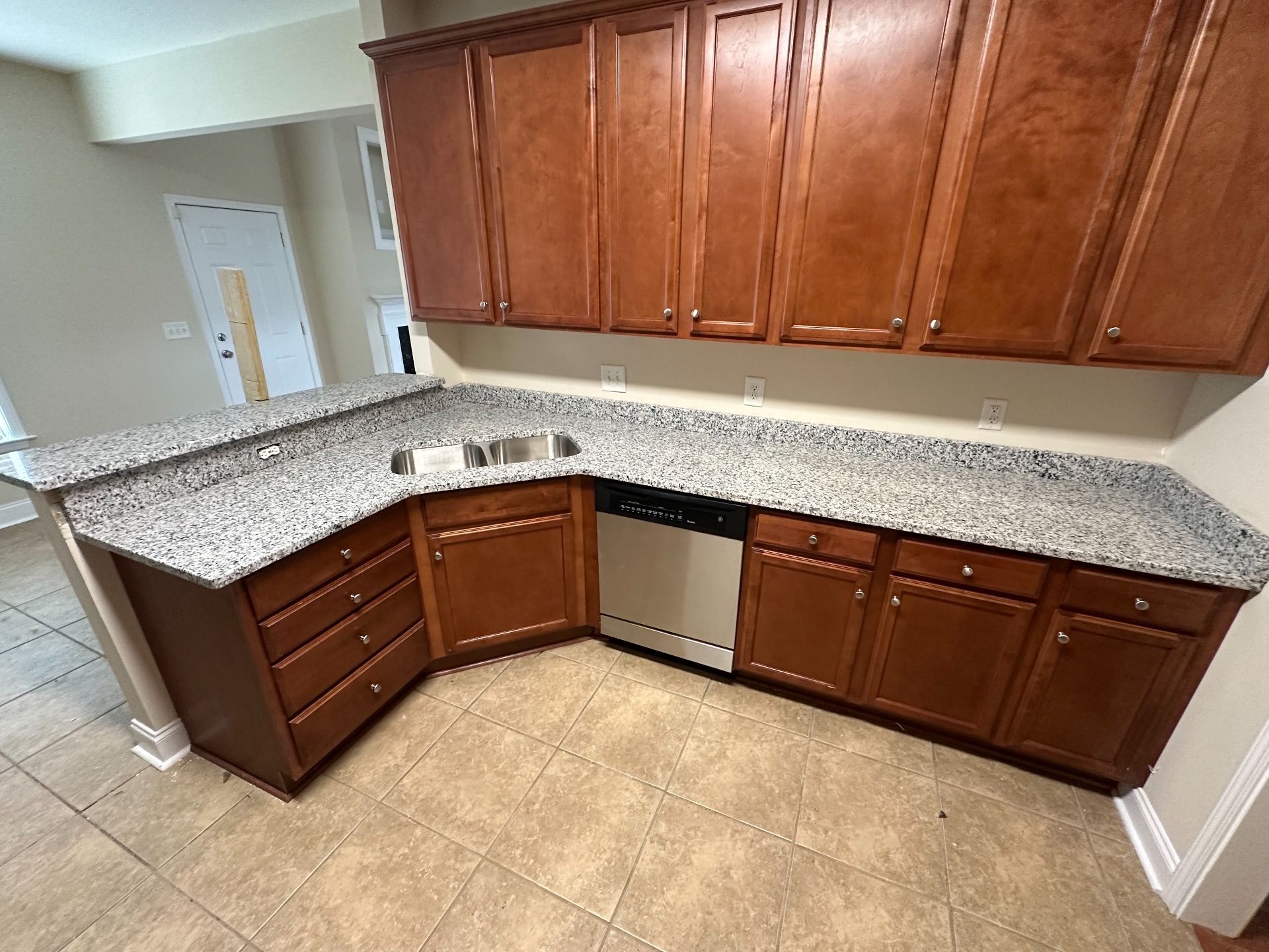 Kitchen with brown cabinets, granite countertops, and stainless steel dishwasher.