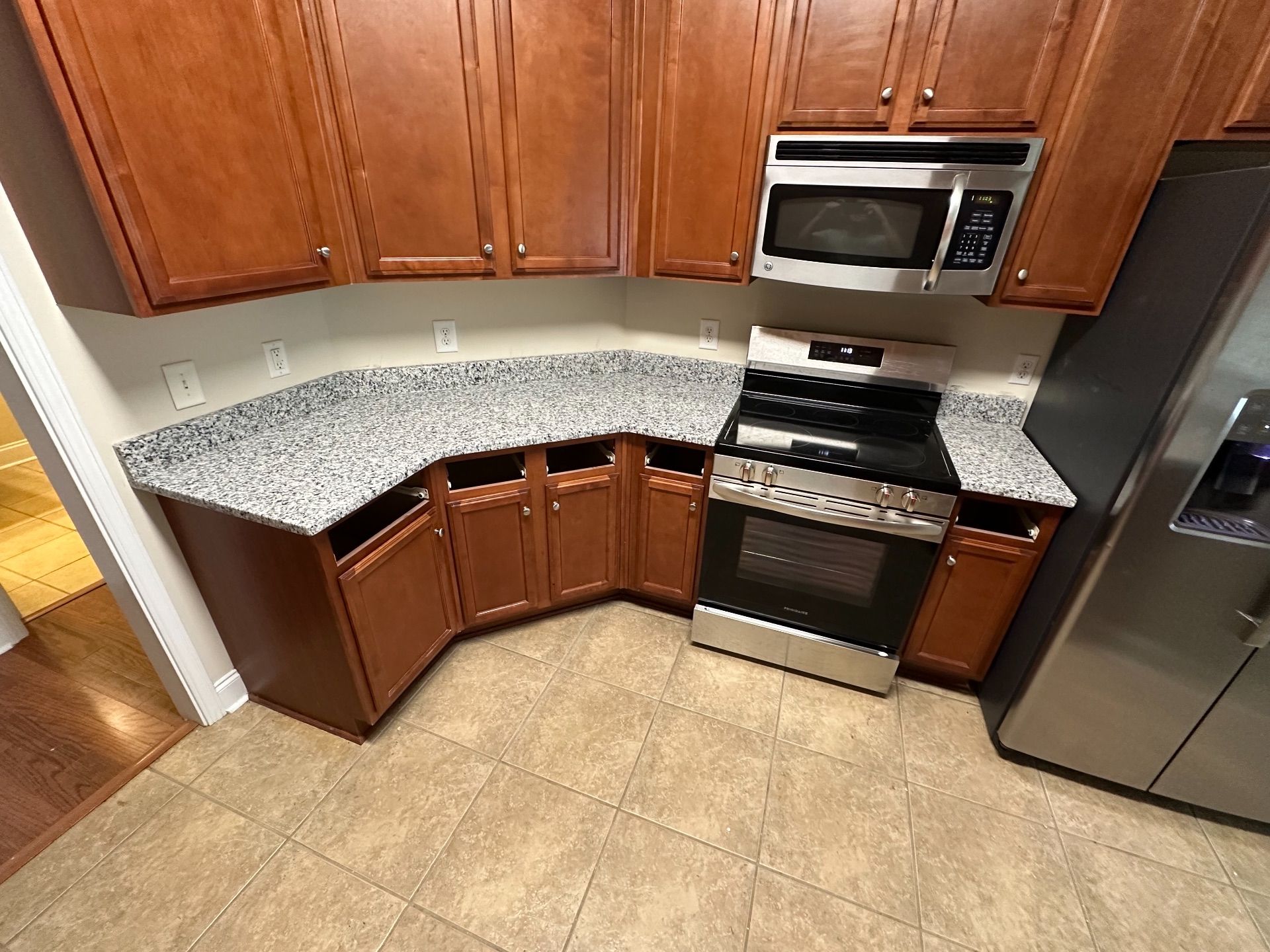 Kitchen with granite countertops, brown cabinets, microwave, and stainless steel oven.
