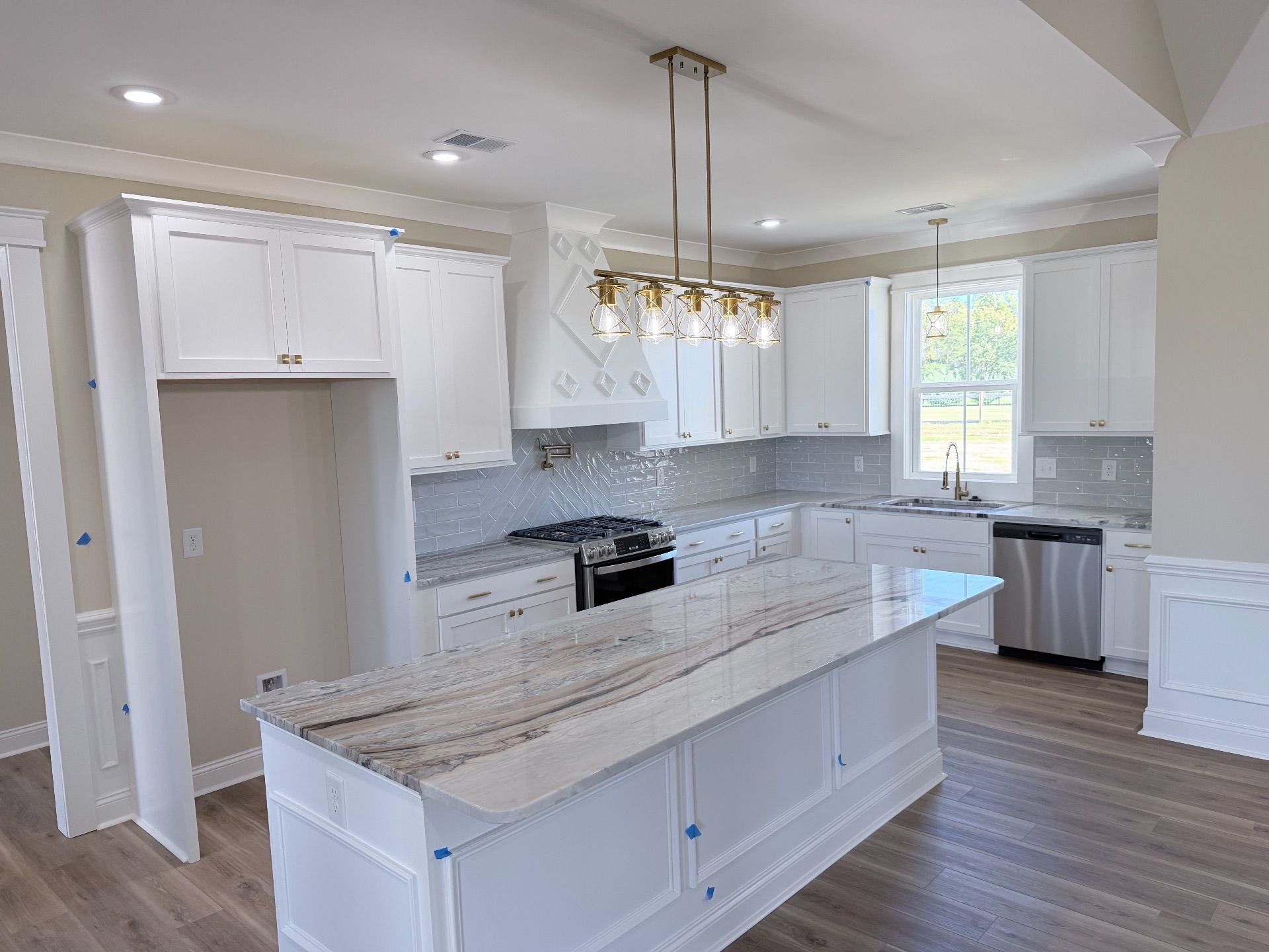 White kitchen with an island, countertops, cabinets, and appliances.