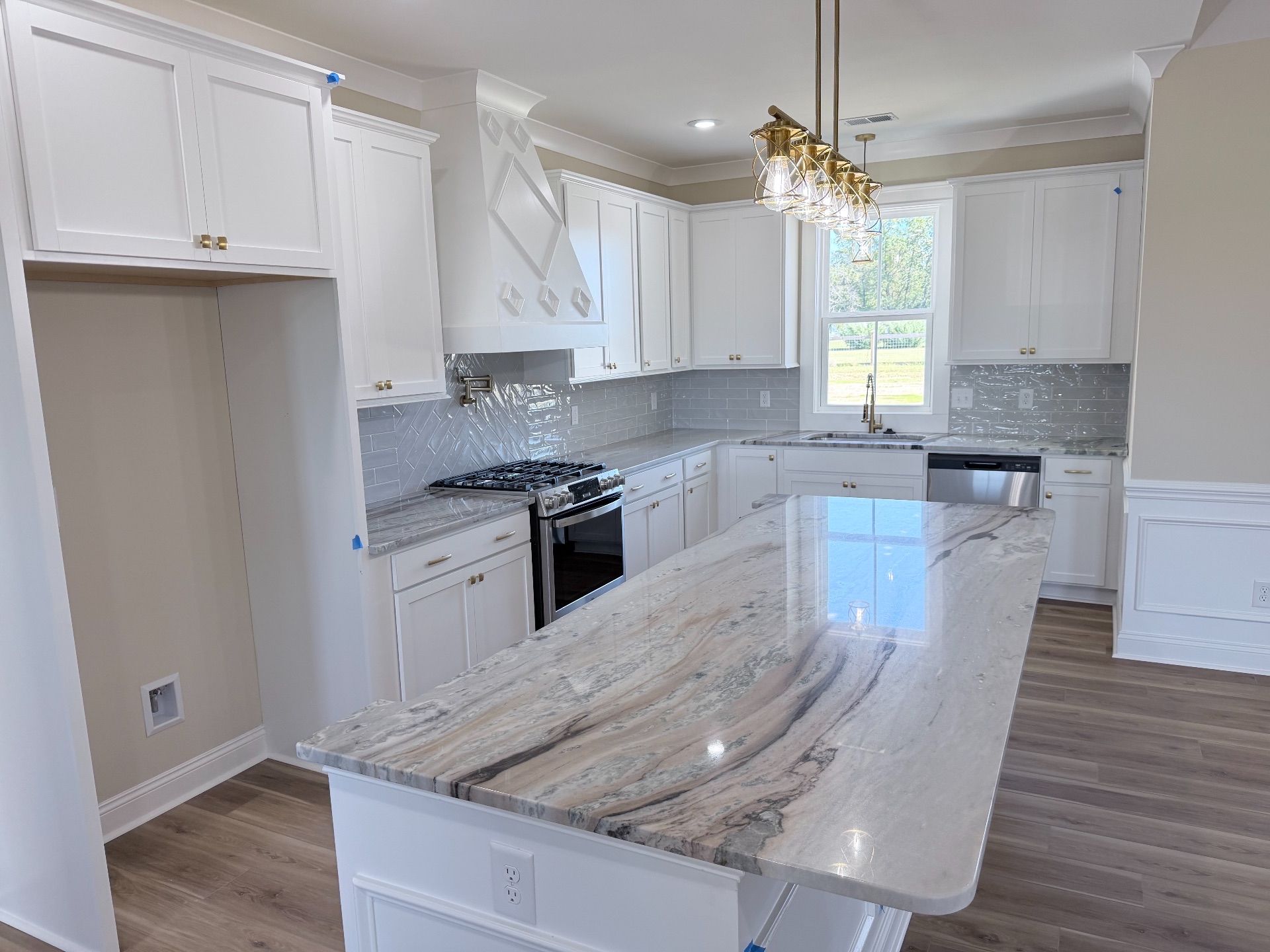 White kitchen with granite island, cabinets, and appliances.