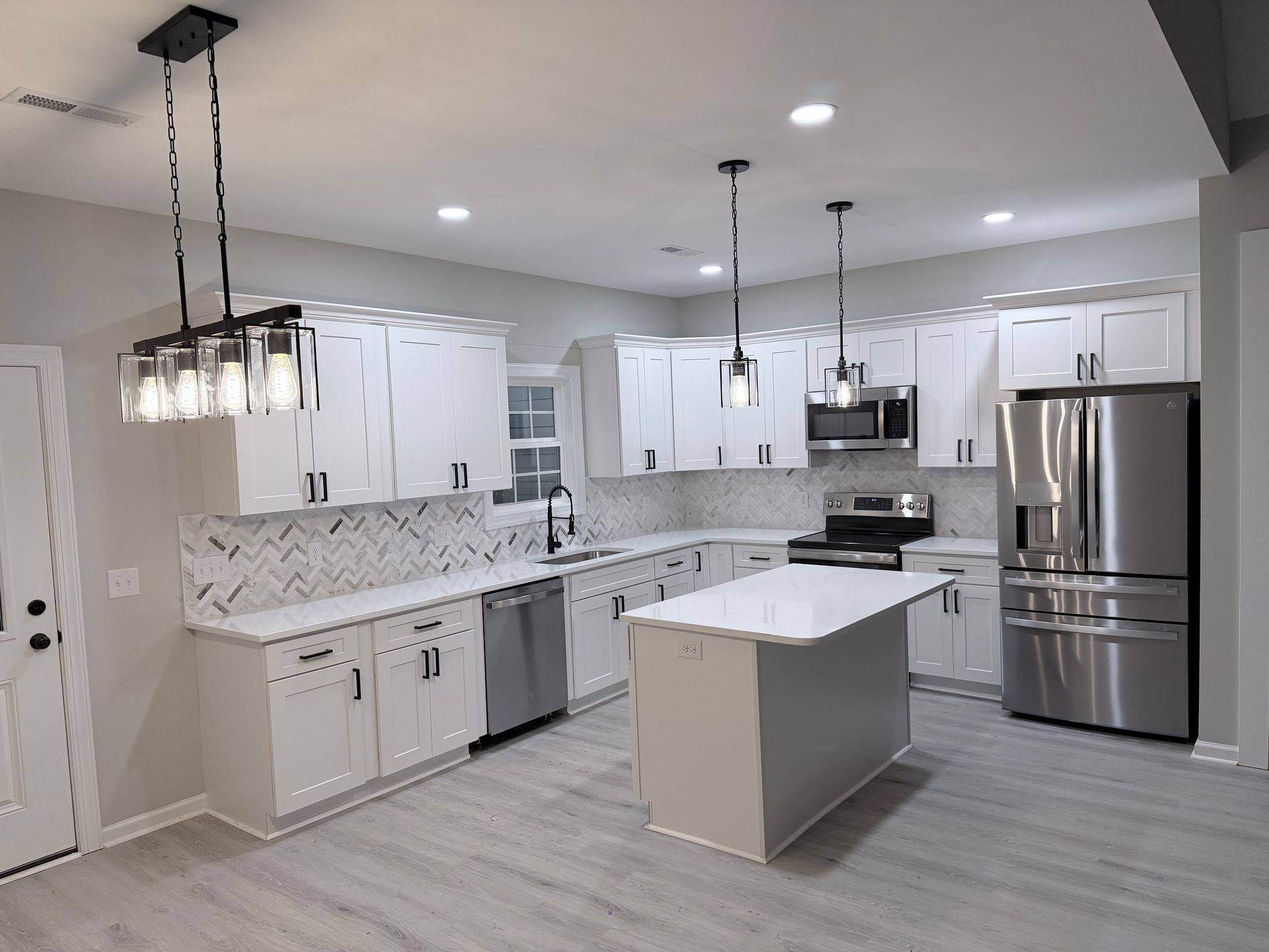 Bright white kitchen with a large island, granite countertops, and stainless steel appliances.