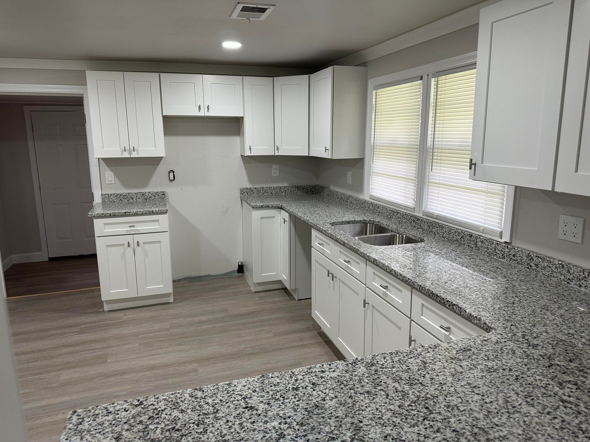 White kitchen cabinets and granite countertops with a sink.