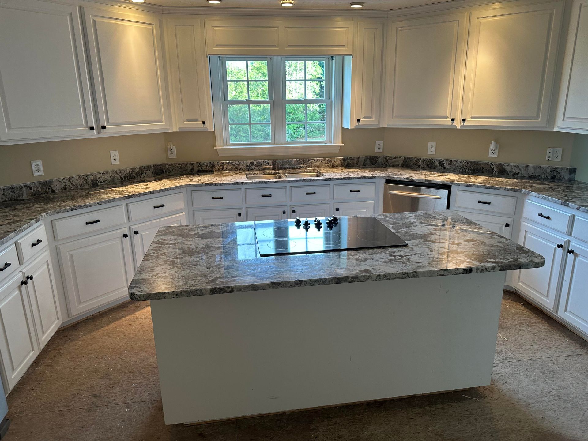 White kitchen with granite countertops and island; stainless steel appliances.