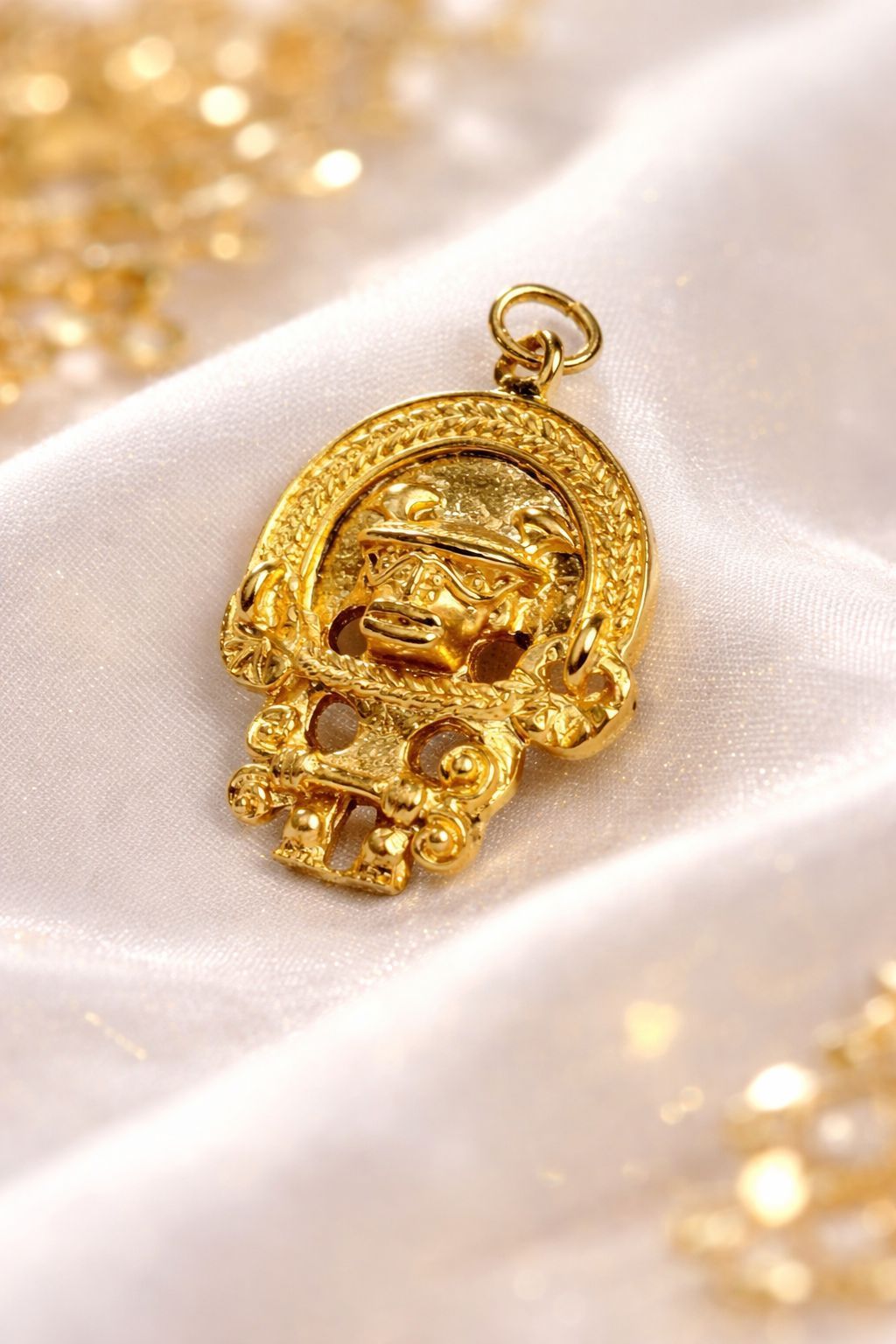 Un collar de oro con un colgante de medallón circular detallado, que se lleva sobre una blusa blanca.