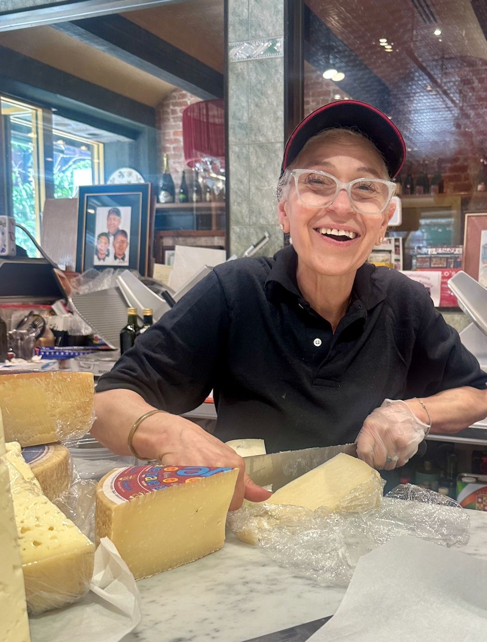 Local Little Italy shop owner cutting fresh Italian cheese behind the counter in New York City