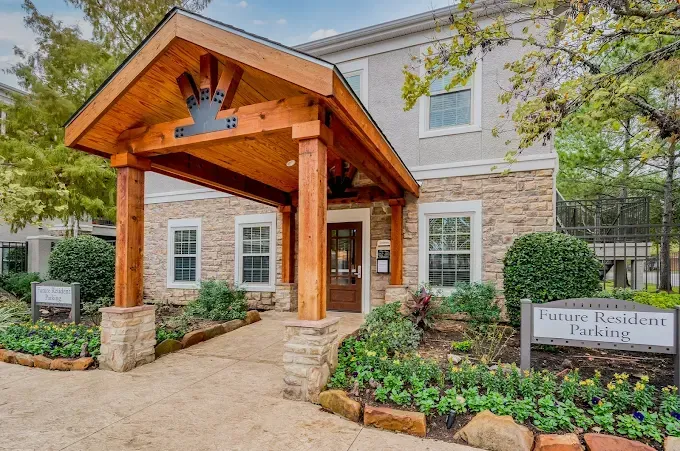 Entrance to building with wooden portico, stone facade, and landscaping.