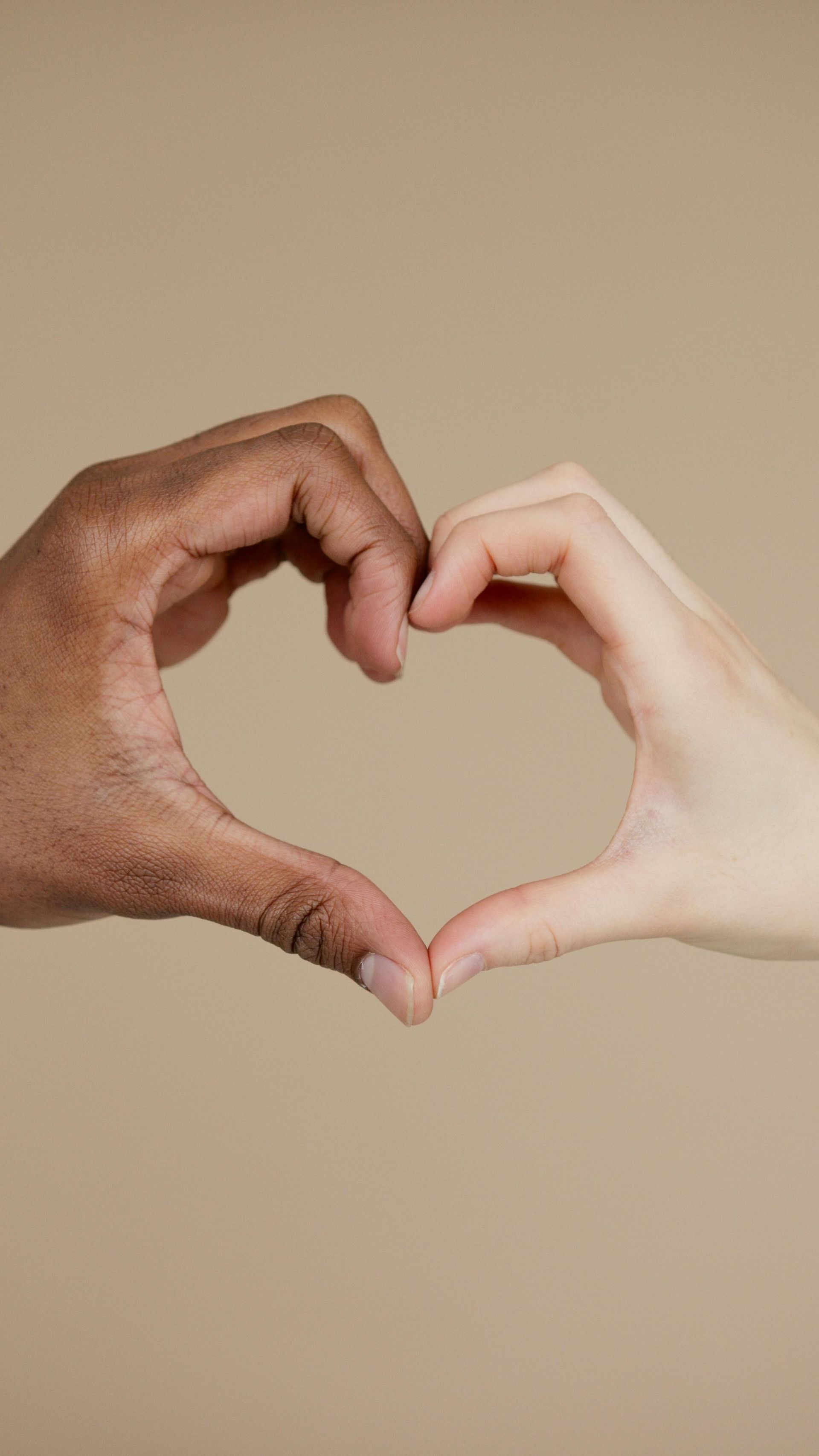 Two hands together symbolizing a heart. One hand is black, the other white