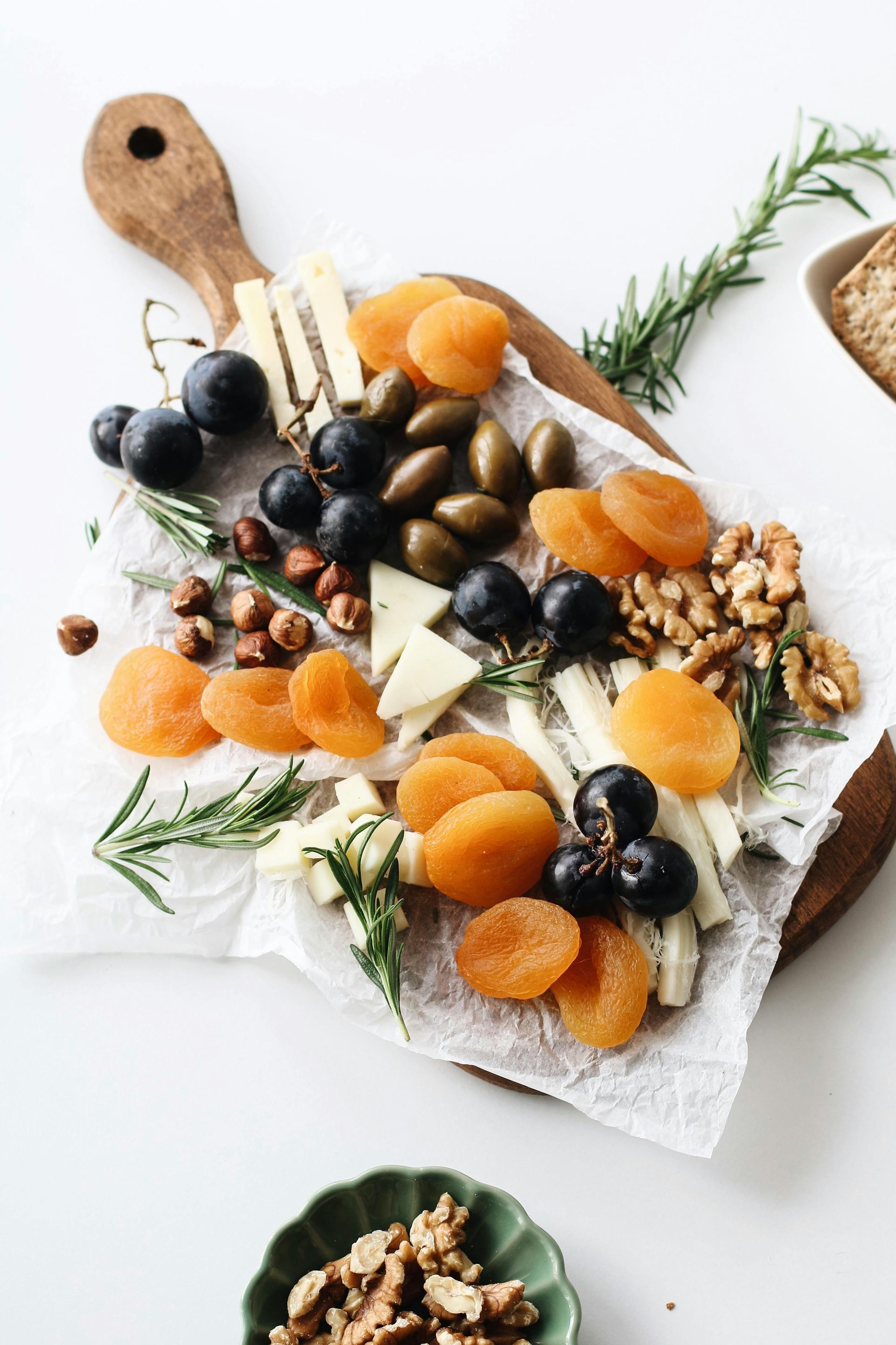 A wooden cutting board topped with dried fruits , nuts and cheese.