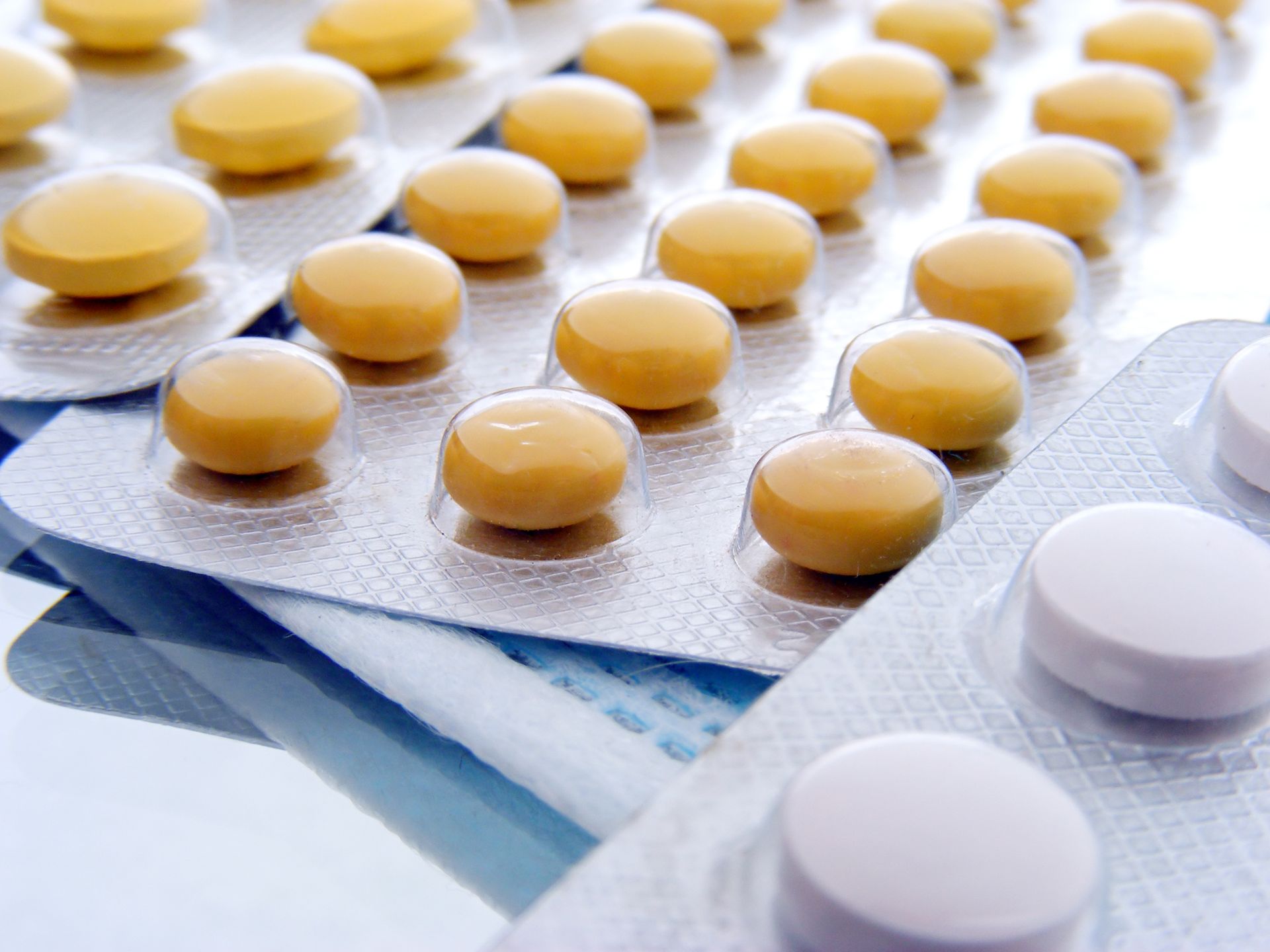 A bunch of yellow and white pills in blister packs