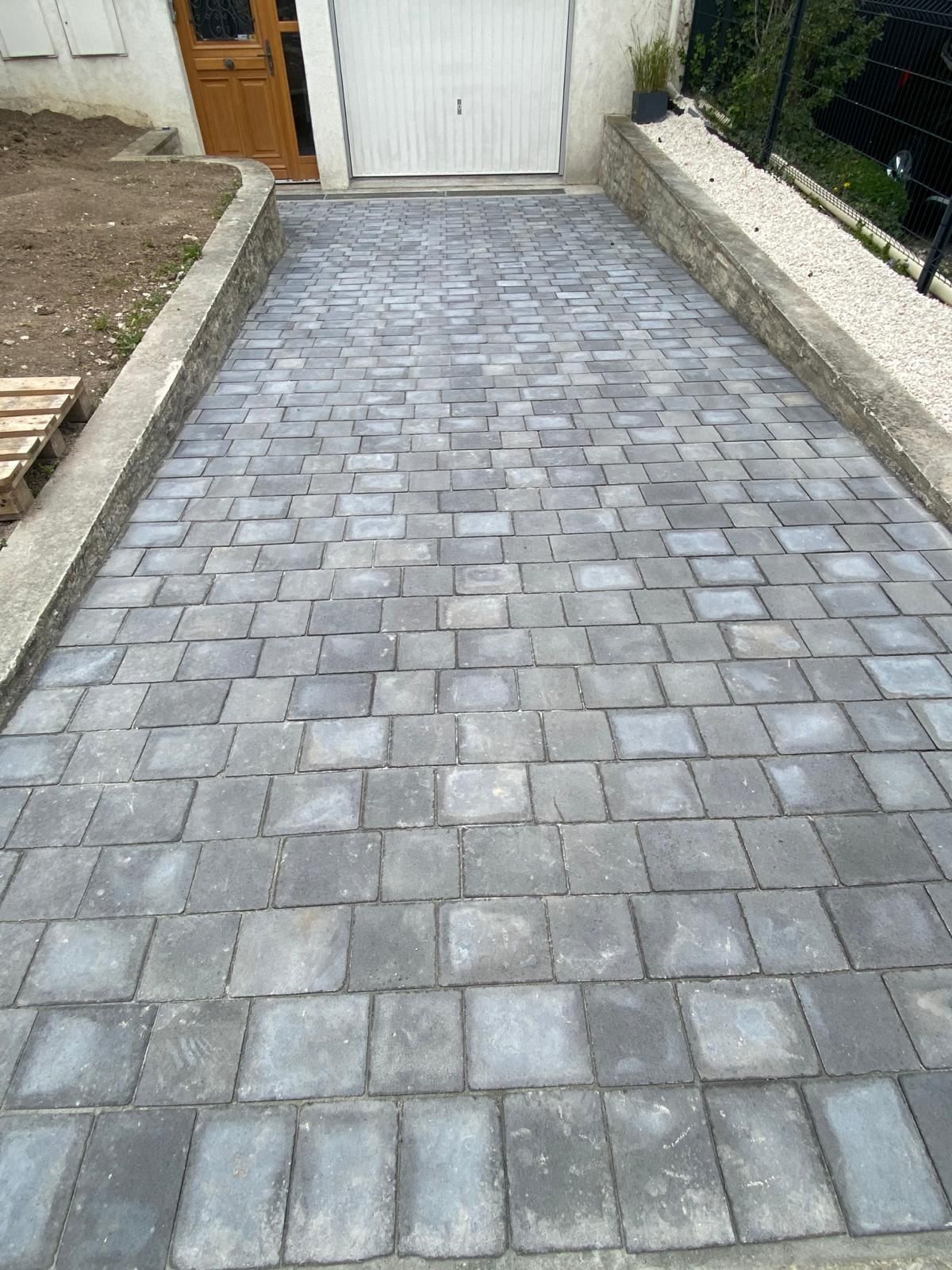 Une allée en brique est en cours de construction devant un garage.